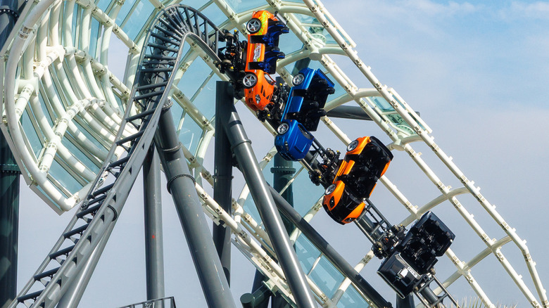 A photo of the four cars on the new ride as they drift around a corner enclosed by a sound shield