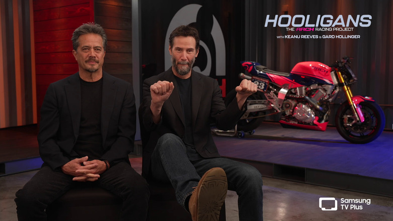 Gard Hollinger and Keanu Reeves talk in front of an Arch bike
