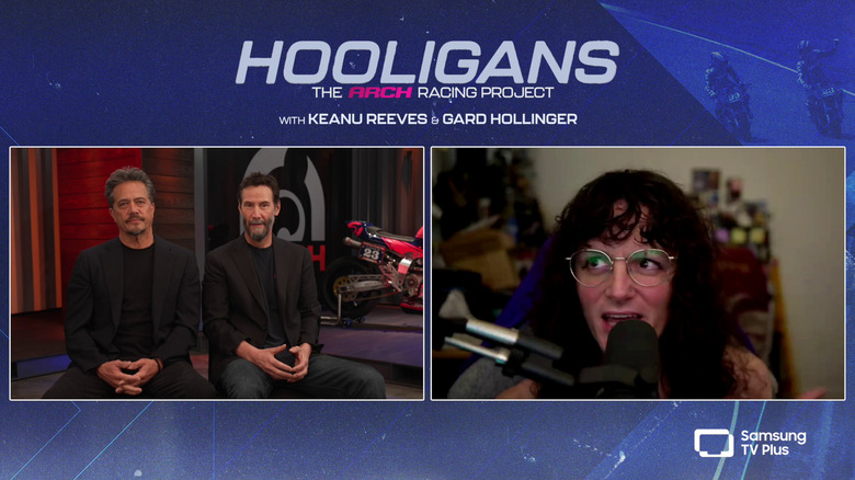 Gard Hollinger and Keanu Reeves talk in front of an Arch bike, with Amber in an adjacent window