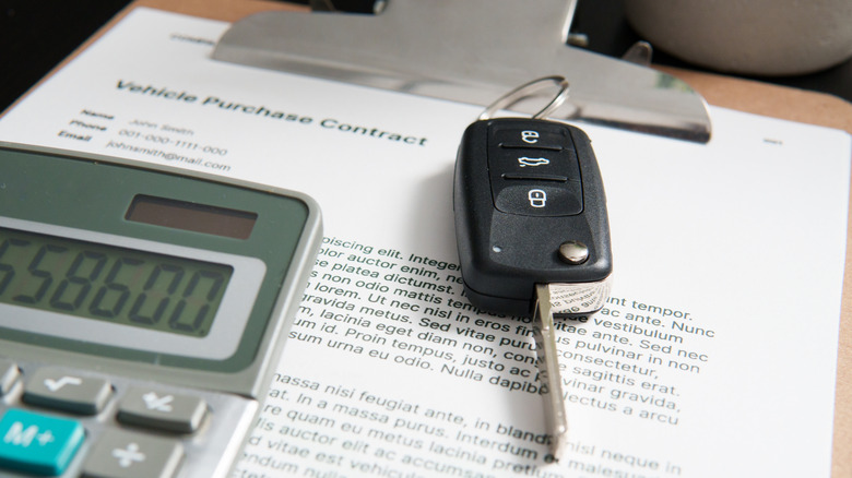 Car keys placed on paper sheets next to a calculator.