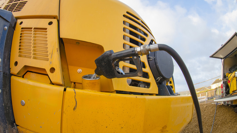 A close-up of a yellow diesel-powered piece of construction equipment refueling.