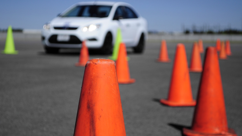 Blurry white car in the background with orange traffic cones